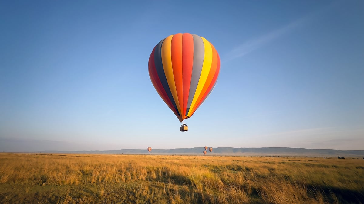 Hot air balloon drifting over the savannah under a clear blue sky